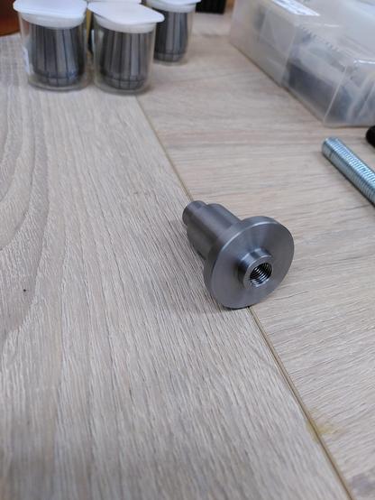 A turned metal part. Looks like a top-hat with a 10mm threaded hole at the bottom.