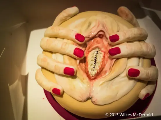 Photo by Wilkes McDermid of a vagina dentata, a vagina with teeth, spread wide by two hands with red nail polish on them.