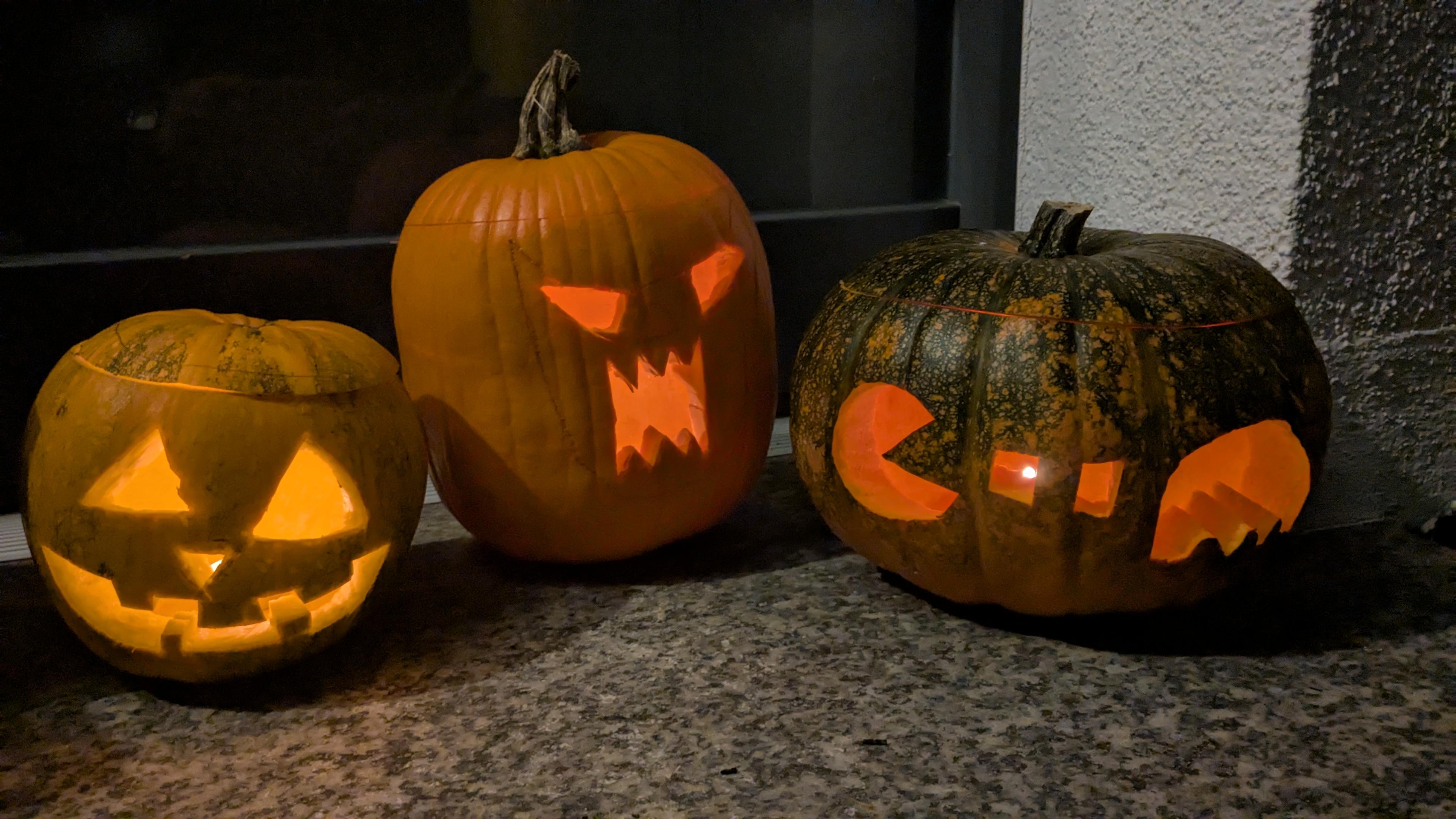 Three Halloween pumpkins: One traditional, one with serrated mouth, and one with pacman two dots and a monster glowing in the dark.