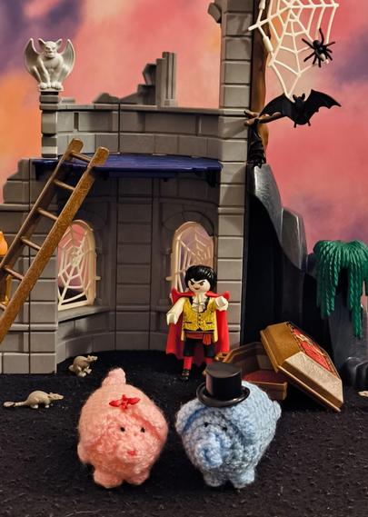 Ein haekelschwein-Pärchen im Vordergrund, dahinter eine Burgruine und ein Sarg, dem ein Vampir entsteigt.