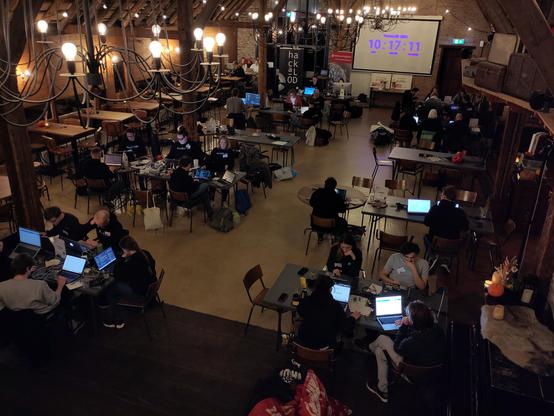 Een sfeervolle ruimte met groepjes hackers achter het scherm met een klok op de achtergrond die laat zien dat er nog tien uur resterende tijd is