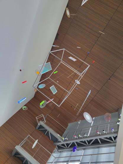 Daytime interior photo of sculpture art "Fertile Ground" by Cork Marcheschi. This view is from underneath, and a bit closer to a large wire-frame cube.