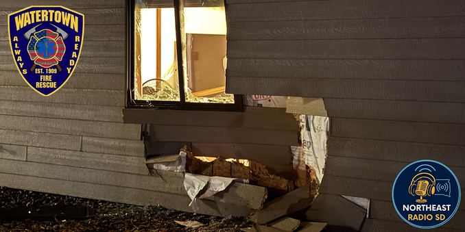 Building exterior with a large hole under a window, lit from inside. "Watertown Fire Rescue" and "Northeast Radio SD" logos visible.
