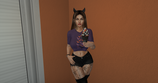 A female Caucasian avatar faces you wearing a purple cropped t-shirt with orange, pink, and black bats flying vertically in the center. Her hair is a very dark blonde with brunette streaks, pulled back with a black headband that has horns. She carries an orange and black ice cream cone decorated with white spooky faces in her left hand and wears a black watch on her right writs. She stands in front of an orange-colored wall.