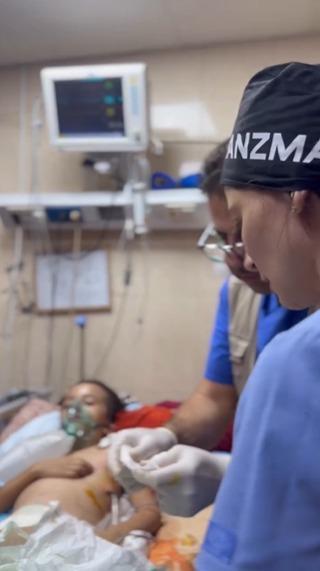 Two doctors from Panzma work in a hospital in Gaza attending a sick young boy.
The boy lies on the hospital bed with an oxygen mask on his face.