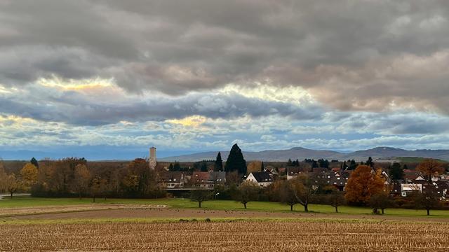 Landschaft (Gundelfingen) mit tiefen Wolken, im Hintergrund Berge.