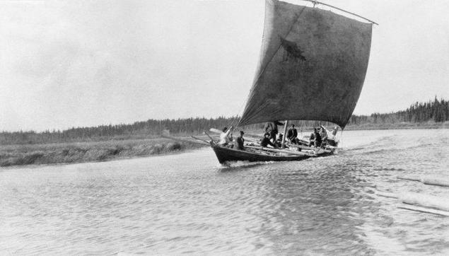 A York Boat sails along a rock bound river with the wind coming from its starboard side.