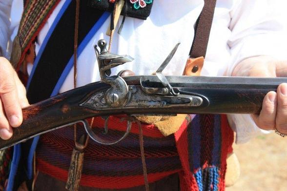 A man of Scottish descent shows the lock of his flintlock gun.