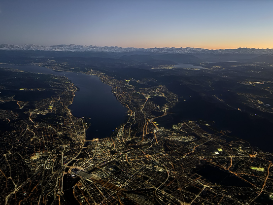 Blick auf den Zürichsee von oben bei Abenddämmerung mit den Alpen im Hintergrund