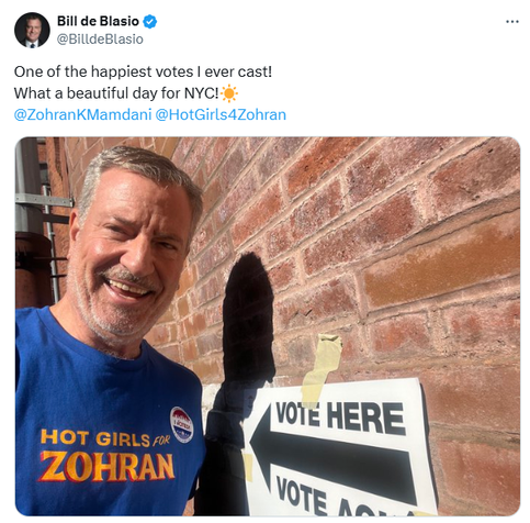 Bill de Blasio & we.
(3) @BilldeBlasio
One of the happiest votes | ever cast!
What a beautiful day for NYC!
@ZohranKMamdani @HotGirls4Zohran

Bill De Blasio to the left of the picture, smiling and wearing a  blue "Hot Girls For Zohran" t-shirt with an "I Voted" sticker on it. He is in front of a 'Vote here' sign on a brick wall. 
