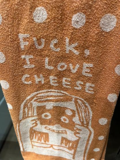 An orange tea towel with a girl peering through some holes in a Swiss? cheese, captioned 

Fuck,
I love
Cheese