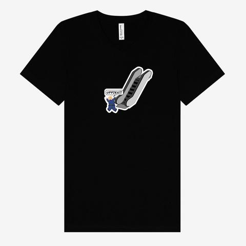 Image of a black crew neck t-shirt featuring a design of a toddler version of Trump in his usual blue suit stranded at the bottom of the escalator saying, “Uppies!!!”,
