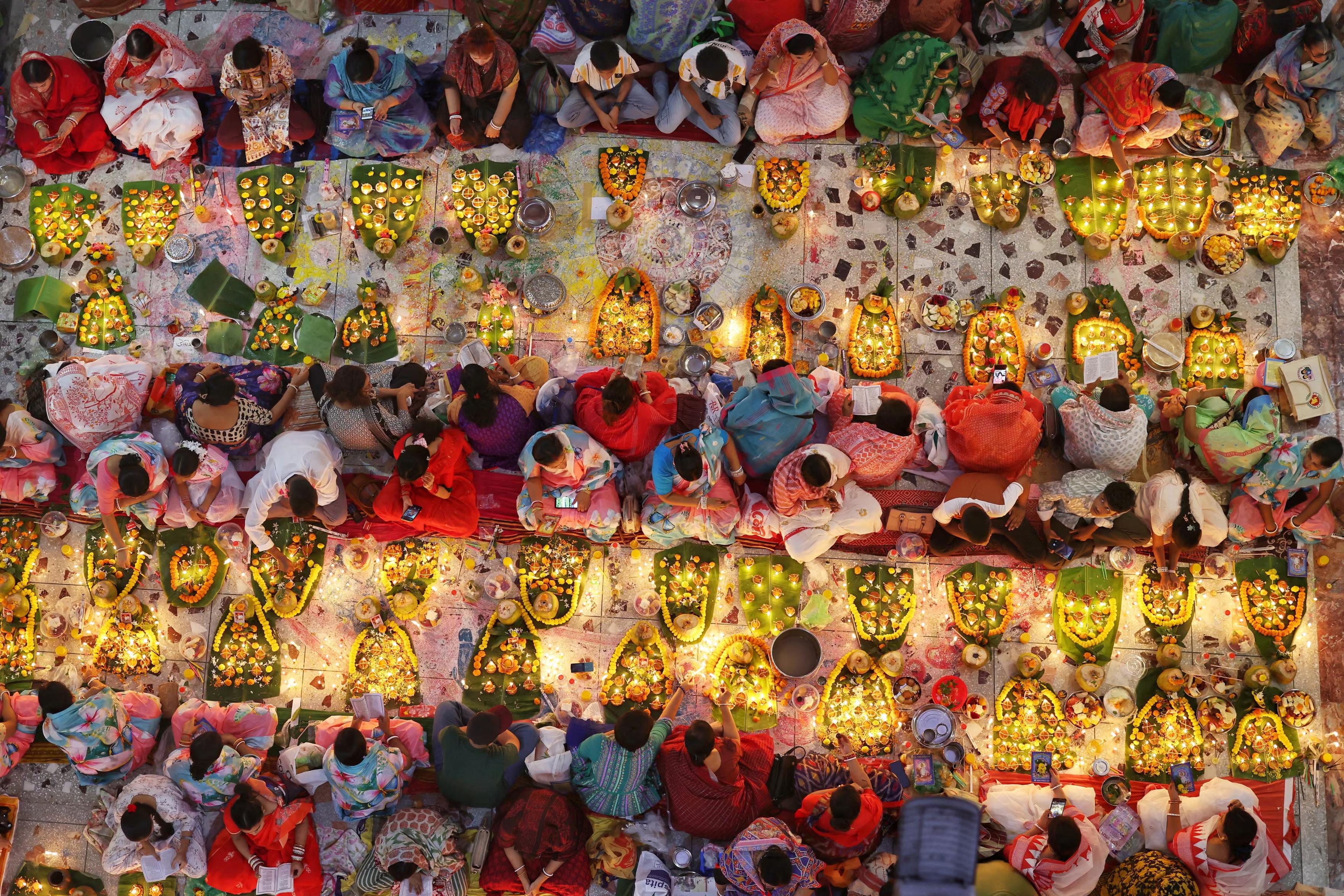Hindu devotees sit together with oil lamps.