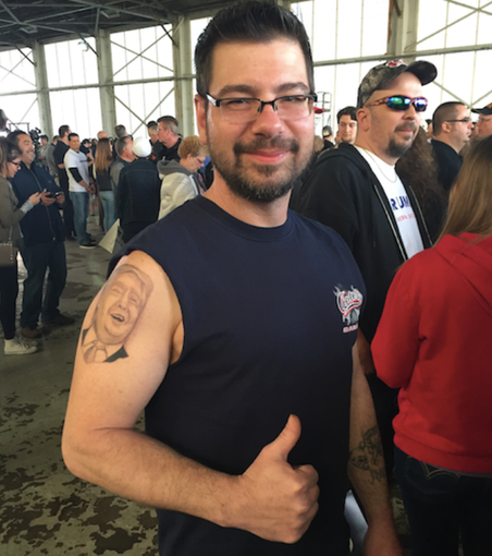Photo of man with a Donald Trump portrait tattoo on his upper arm. 