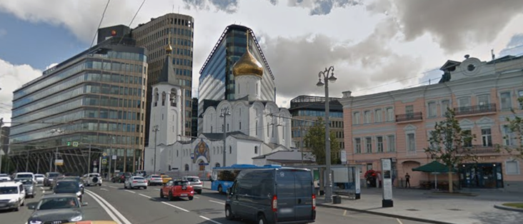A photo of a church in front of the business center, the latter is much higher 