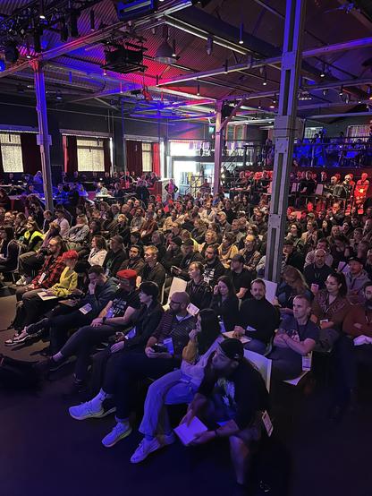 Room with attendees at beyond tellerrand. Lights are set to a red and blue scene