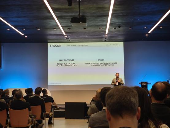 view of the stage at SFSCON 2025, with a speaker and slide.