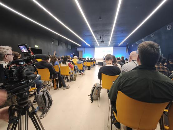 view of the stage at SFSCON 2025, with a speaker and slide.