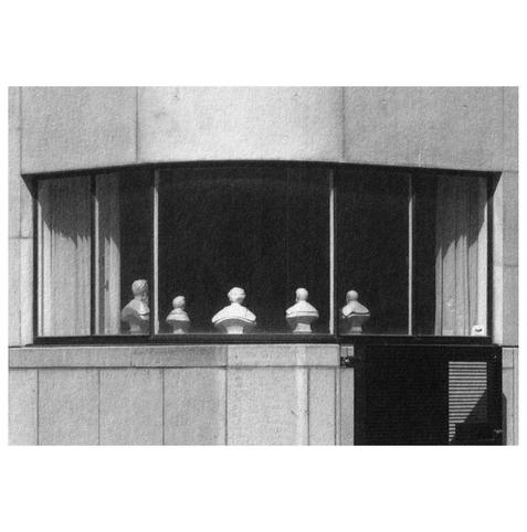 The cover art for Lia Kohl's Various Small Whistles and a Song album, showing busts on display behind a large curved window, set against a concrete wall. Black and white image, with a calm, architectural mood.