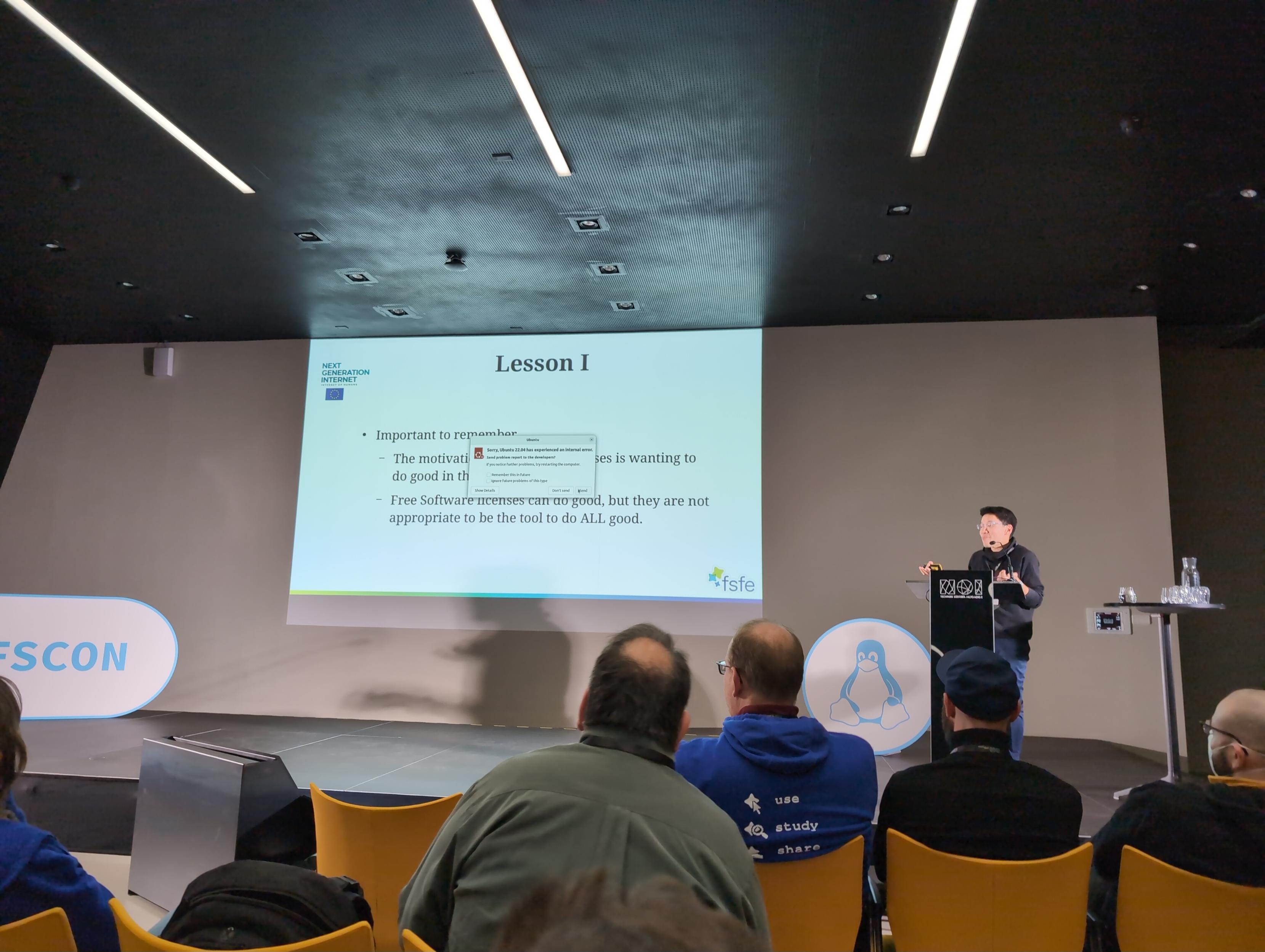 Conference stage with an Ubuntu error dialog in the middle of the slides.
