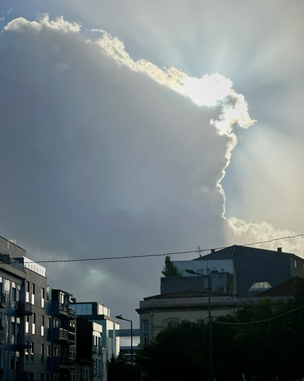 The sun peeking out from a large cumulus cloud in Braga Portugal 