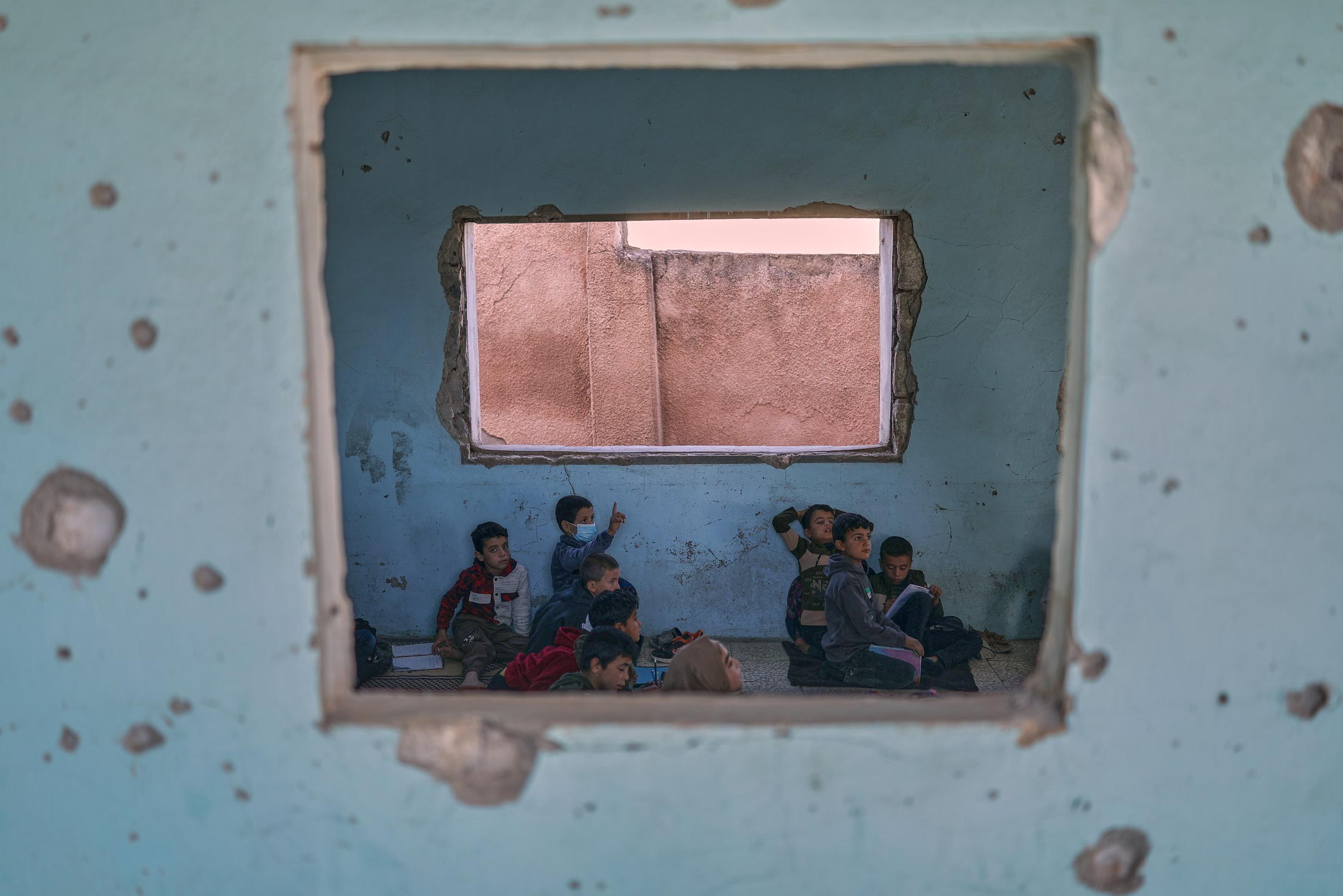 Students attend class at the Maar Shamarin primary school. The school’s walls remain scarred by bullet holes.