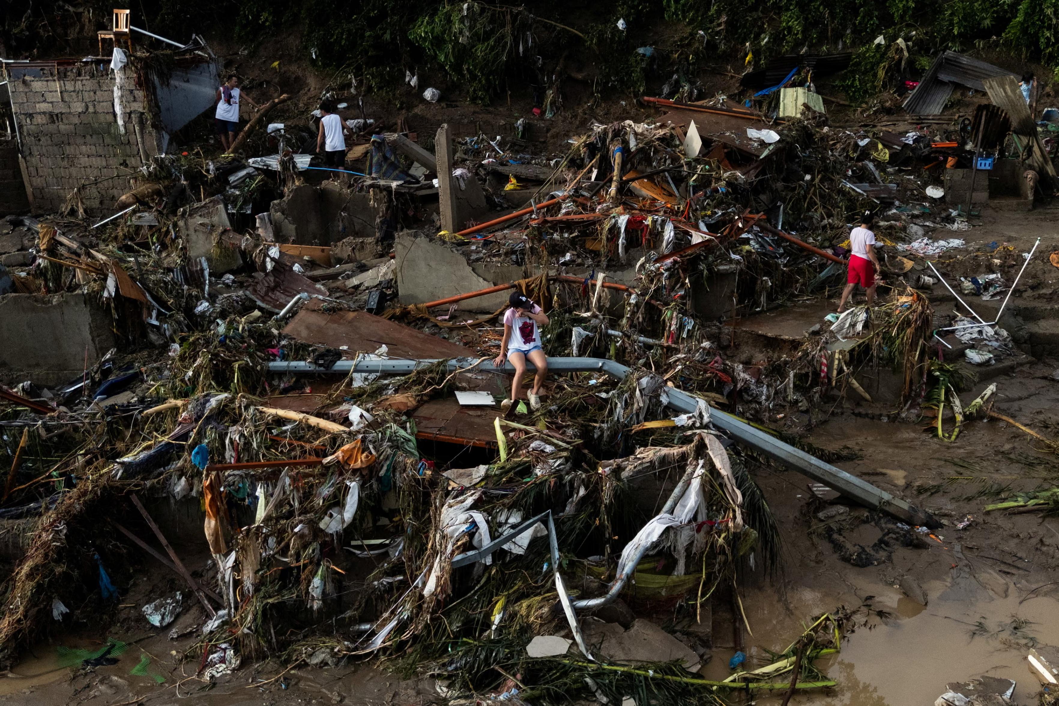 A woman sits on a fallen post amid damage caused by Typhoon Kalmaegi.