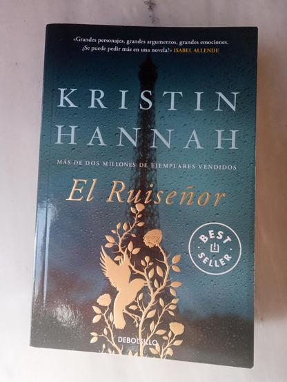 El Ruiseñor, de Kristin Hannah, editado por Debolsillo en 2020. Traducción de Laura Vidal. La cubierta muestra la silueta de la Torre Eiffel, a través de un cristal mojado por la lluvia, en tonos oscuros y, superpuesta sobre la base, un relieve dorado de un ave en un rosal.