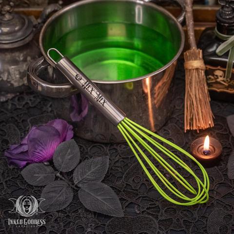 One bright green "Hex Mix Whisk" stands against a small steel pot containing a green liquid. The whisk has bright green loops and a grey stainless steel handle. The handle is engraved with a tiny IGC logo and the words "Hex Mix." This is an exclusive product from Inked Goddess Creations.