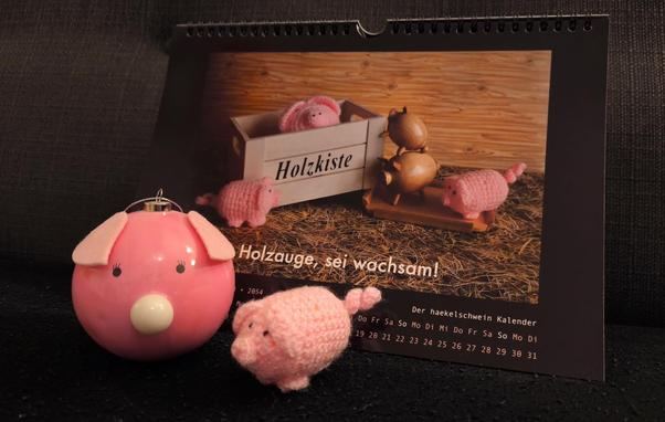 Ein haekelschwein und eine Schweinchen-Kugel mit Leuchtnase vor einem haekelschwein-Kalender.