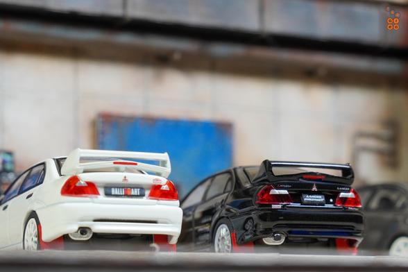 Two cars of Mitsubishi Lancer RS Evolution.
One is Evolution 6, Monte Carlo Edition, Scortia White and one is Evolution 5, Pyrenees Black. 
Both by Hobby Japan in 1:64 scale on AREA 164.