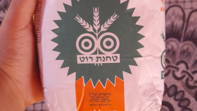 Naeema's hand holding a bag of flour.