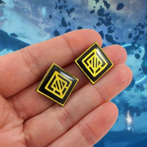 Puces d'oreilles fantaisie éco-responsables en forme de losanges noirs ornés de motifs dorés. Elles sont inspirées par les luminas dans le jeu vidéo "Clair Obscur : Expédition 33".
Les perles sont réalisées en CD recyclé, découpées et peintes à la main, puis recouvertes de résine.
Les tiges sont en acier inoxydables.