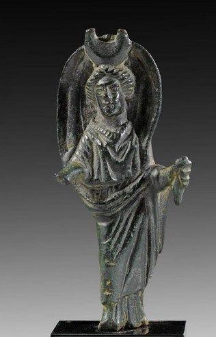 Charming little bronze figure depicting the moon goddess Selene with a huge lunar crescent on her head and her iconic billowing cloak and torch. An appealing dark green patina covers the figurine.