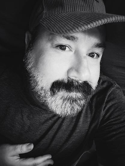 Black and white selfie. I'm a bear man with mustache and beard wearing a cap.