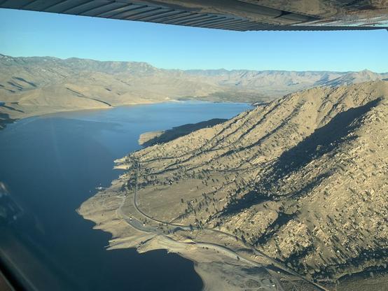 A lake between sandy mountains, seen from the air below blue skies