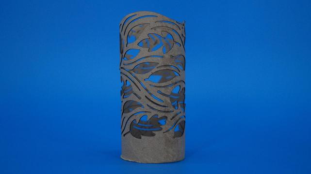 Zylindrische Laterne aus einer Klopapierrolle mit herbstlichem Wirbelmuster, durch das warmes LED-Licht scheint.