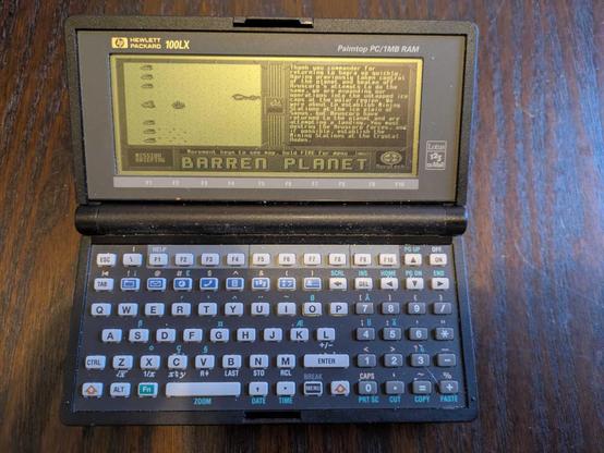 A photograph of a Hewlett Packard 100LX running the downloadable Barren Planet campaign The Polar Expedition, showing the Nuvutech briefing for the first mission.