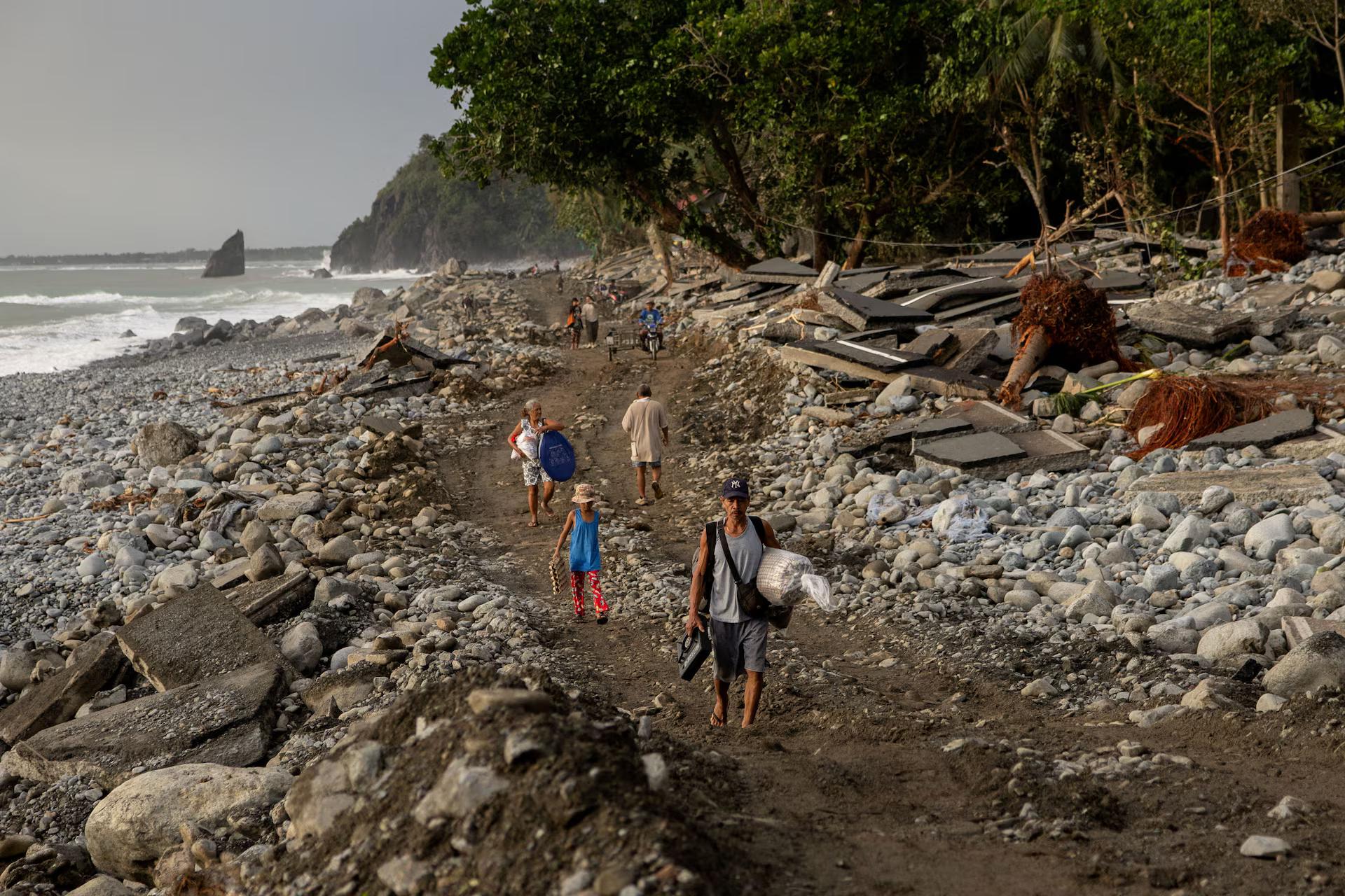 Residents walk along the damaged portion of the Baler-Casiguran road that was damaged by storm surges brought on by Typhoon Fung-wong, in Dipaculao, Aurora.