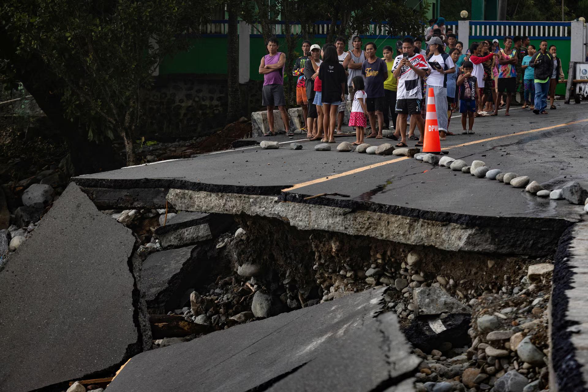 People stand near a wrecked part of the Baler-Casiguran road a day after Typhoon Fung-wong made landfall in Dipaculao, Aurora.