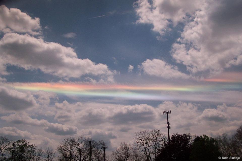 For a circumhorizontal arc to be visible, the Sun must be at least 58 degrees high in a sky where cirrus clouds are present. Furthermore, the numerous, flat, hexagonal ice-crystals that compose the cirrus cloud must be aligned horizontally to properly refract sunlight in a collectively similar manner. Therefore, circumhorizontal arcs are quite unusual to see. This circumhorizon display was photographed through a polarized lens above Dublin, Ohio in 2009.