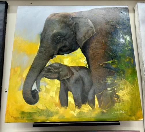 two elephants, one large, one smaller, seen from the side, the baby one nuzzling its trunk against the older one, they are surrounded by bright yellow grasses 