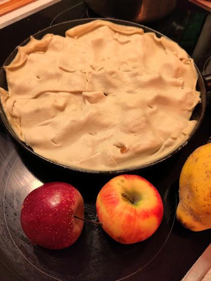 And, off to the oven...

A pan filled with apples covered with pastry, next to it 2 apples and quince.