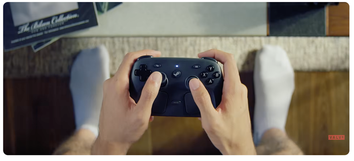 Close-up of a person's hands holding a Steam Controller, highlighting the position of the dual touch panels under the thumbs.