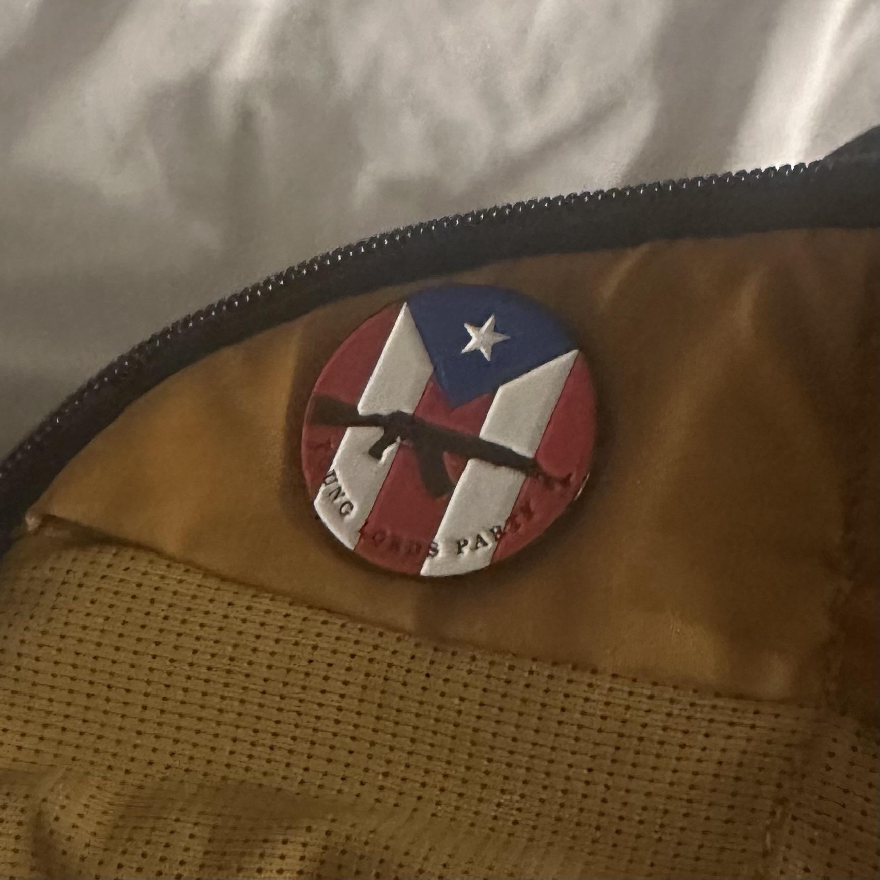 Circle pin of Puerto Rican flag, silhouette of gun and words "Young Lords Party"