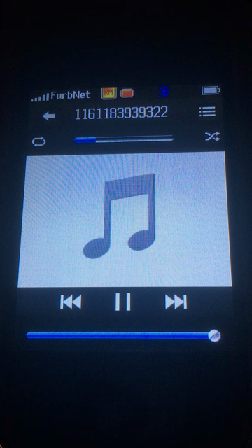 A bootleg iPhone 2G in the music app, playing an MP3 of “She” by Groove Coverage. The file name consists of random numbers, the phone’s carrier is shown as “FurbNet”, and after a bit the camera pans around to show a DIY 2G network setup, before going back to the phone.