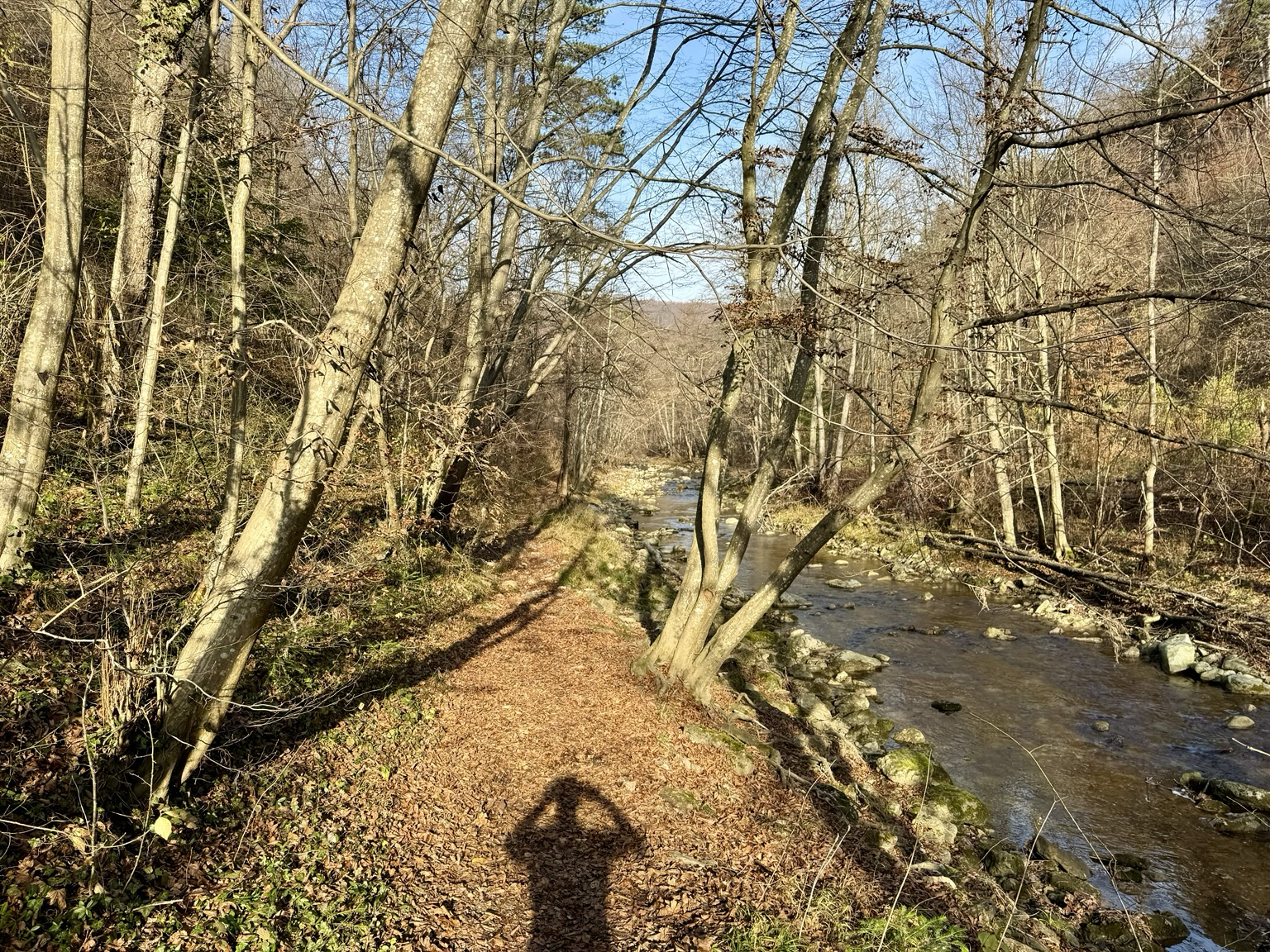 Ein schmaler Pfad in den Bergen schlängelt sich an einem Fluss entlang. SONNE im Rücken, blauer Himmel von oben!