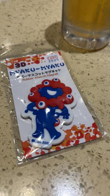 rubber magnet of myaku-myaku, the osaka expo 2025 mascot ... a smiling monstrosity with five eyes in a red circle around a smiling blue body