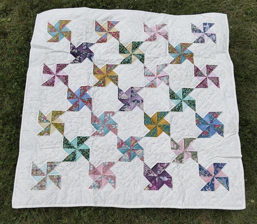 a quilt, it is pinwheel designs in soft colors, against a white background, there are 23 of them in total 