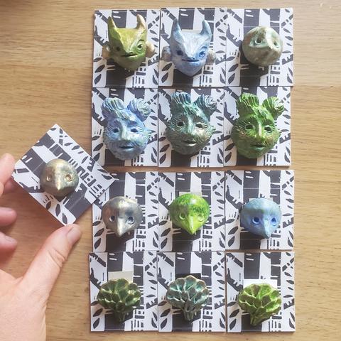 Photo des broches fixées sur de petits cartons avec une linogravure représentant des troncs d'arbre